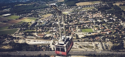 白天城市建筑物上方的红色和白色缆车